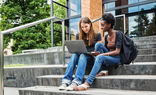 female students on steps with laptop