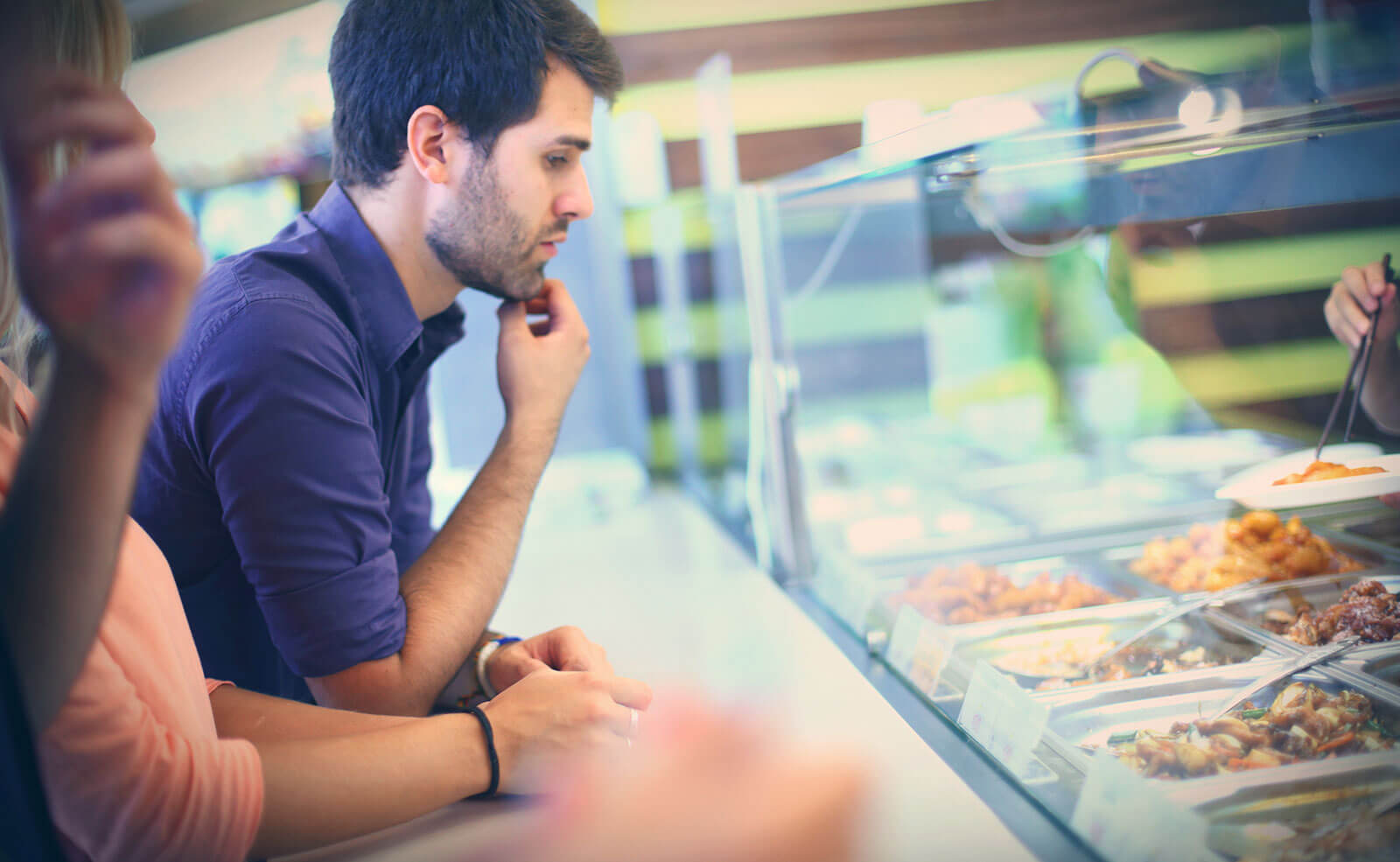 male student looking at food in cafe
